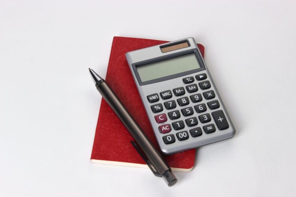 red notebook with pencil and calculator in white background